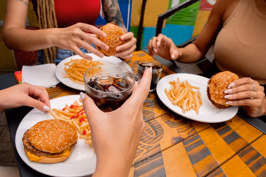 Ungesundes Fast Food in Gesellschaft erschwert das erarbeitete Kaloriendefizit und macht auf Dauer anfälliger für Krankheiten.