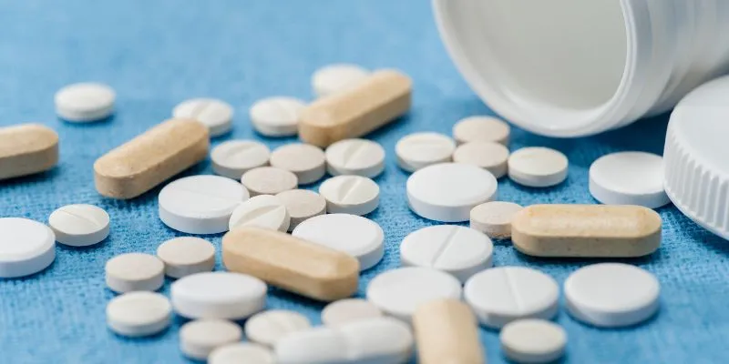 Tabletten und Kapseln neben einer geöffneten Dose.