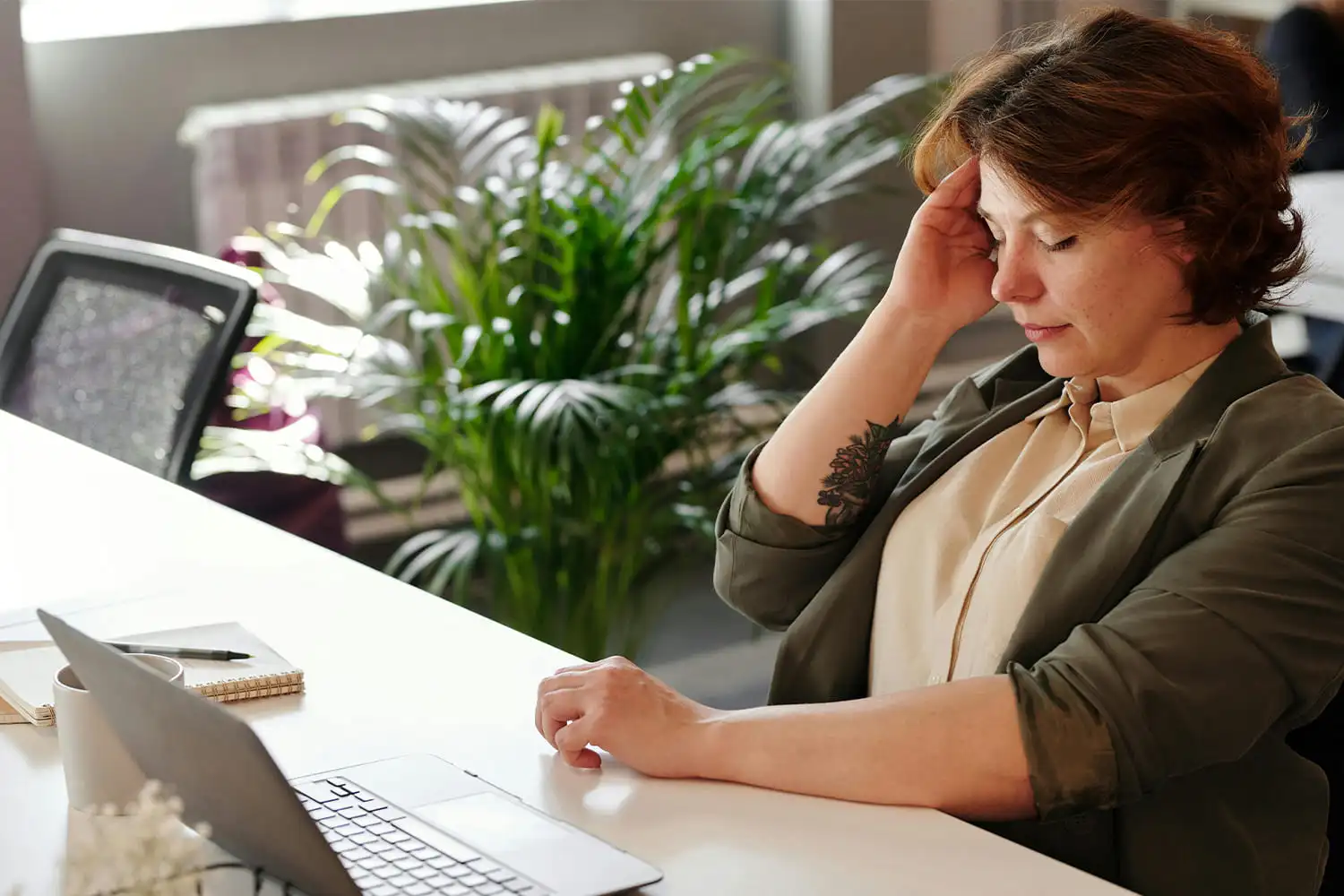 Frau am Laptop stützt die Stirn mit der Hand.