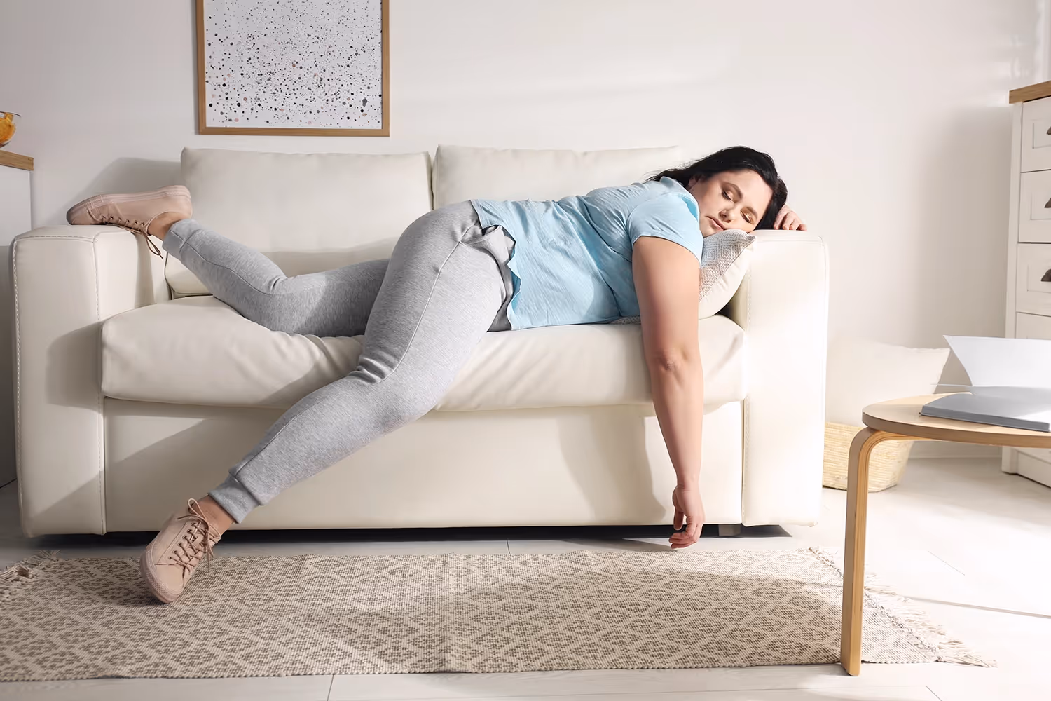 Person liegt quer auf einem Sofa, ein Arm hängt herunter.