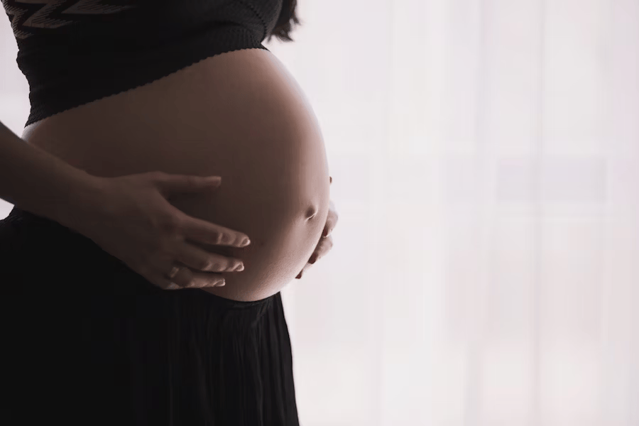 Schwangere Frau nimmt Nahrungsergänzungsmittel, um Nährstoffmangel vorzubeugen.